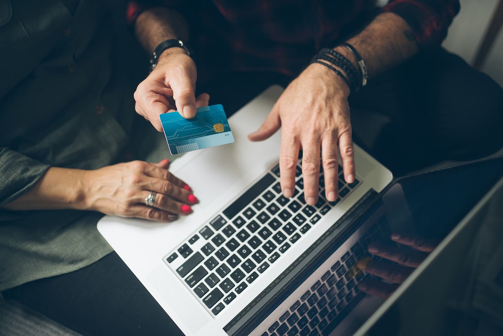 Hands holding a credit card over a laptop keyboard